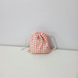 Detail of orange gingham cotton drawstring bag with light blue bow and white cord