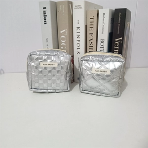 Detail of silver quilted makeup bags with square and diamond patterns and top zipper