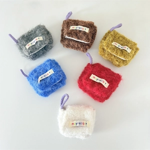 Detailed flat lay of six colorful plush mini earphone pouches with soft fuzzy textures