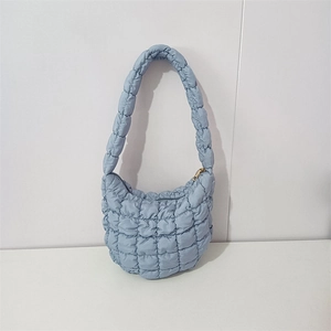 Detailed view of light blue puffy quilted shoulder bag with golden zipper and soft texture