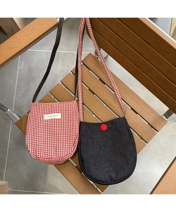 Detail of checkered fabric and denim crossbody bags hanging on a wooden chair