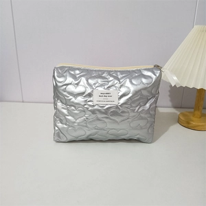 Close-up of silver quilted makeup bag featuring heart stitching and metal zipper detail