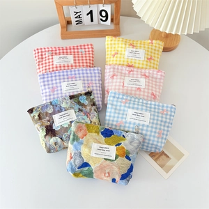 Canvas makeup bags with floral and checkered bow patterns on a clean white table