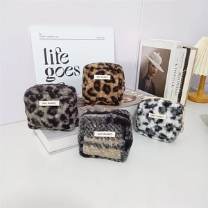 Detailed view of four leopard print plush square pouches on fashion magazines