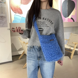 Détail du sac bandoulière en peluche bleu roi avec fausse fourrure et patch logo cuir