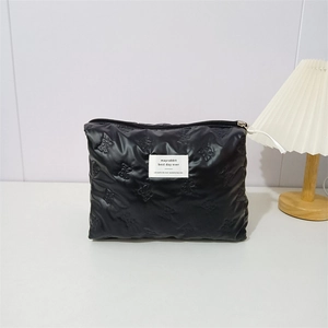 Detail showing black quilted PU makeup bag with bow embossed pattern and brand label