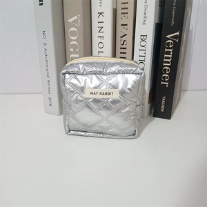 Detail of silver quilted PU cosmetic bag with metallic finish and brand label
