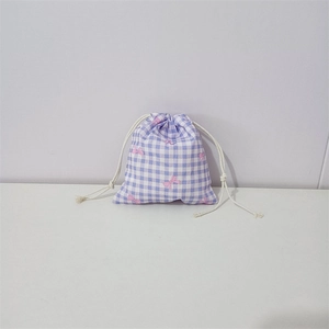 Detail of a purple plaid cotton drawstring storage bag with pink bow floral print