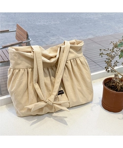 Detailed texture of beige canvas tote bag featuring soft pleats and a decorative bow