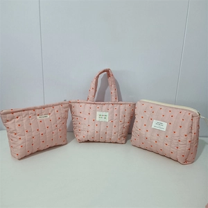 Close-up of three quilted pink bags featuring red heart patterns and soft cotton texture
