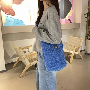 Détail du sac cabas en peluche bleue avec étiquette et texture douce en décor de vie réelle