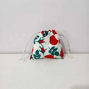 Detail of floral cotton drawstring pouch with red roses and cream braided cords