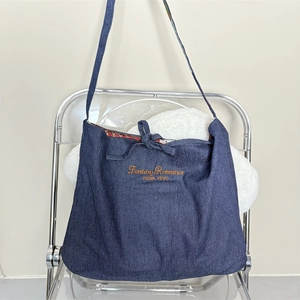 Detail of dark blue denim tote bag with yellow letter embroidery and floral lining