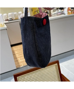Close-up of denim tote bag with red button closure and red-white checkered lining