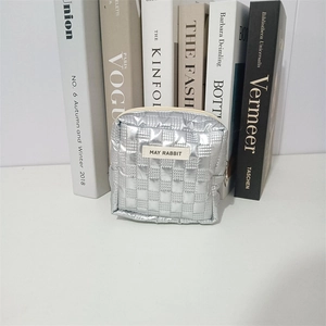 Detailed view of silver quilted makeup bag with MAY RABBIT tag and sleek zipper closure