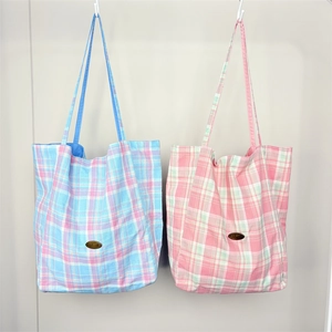 Close-up of blue and pink plaid tote bags with handmade labels and canvas texture