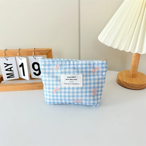 Detail view of canvas makeup bag with blue gingham pattern and pink bow embroidery