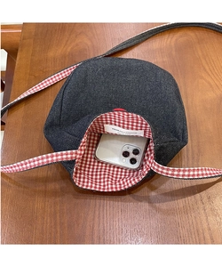 Detailed interior of denim crossbody bag showing gingham lining and smartphone storage