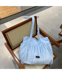 Detail of light blue linen tote bag featuring pleated design and romance woven label