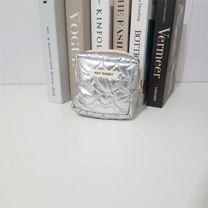 Detailed view of silver quilted PU cosmetic bag with heart-shaped texture and brand label