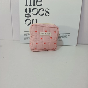 Macro detail of pink quilted fabric with red hearts and a zipper on a vanity pouch