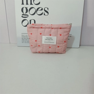 Close-up of pink quilted cosmetic bag with red heart pattern and silver zipper detail