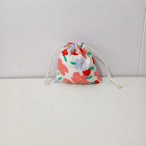 Close-up of floral print cotton drawstring bag with colorful blossoms and beige ropes