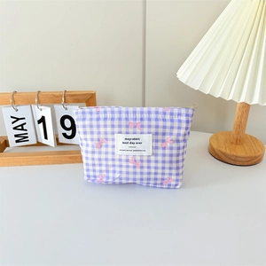 Close-up of a purple gingham makeup bag with pink bows and a zipper closure
