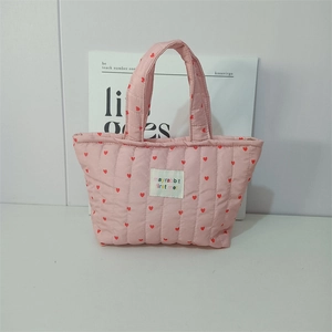 Detail of pink quilted handbag with red hearts and embroidered brand logo label