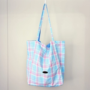 Detail of pink and sky blue checkered tote bag with a black oval logo and long shoulder strap
