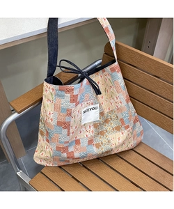 Detail of the large canvas patchwork tote bag with floral patterns on a wooden bench