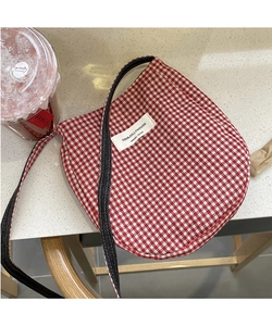 Close-up of red and white plaid fabric phone bag with designer label on marble surface