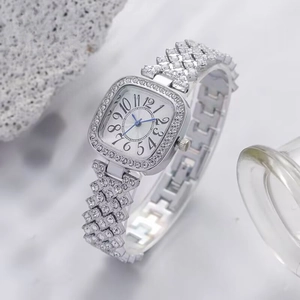 Détail de la montre carrée avec strass, aiguilles bleues et chiffres arabes clairs