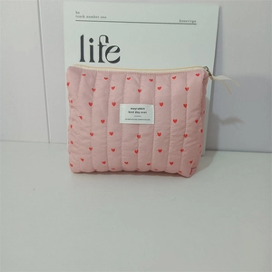 Detail of pink quilted storage bag with red heart patterns and a white woven label