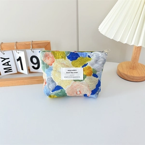 Detailed view of impressionist floral canvas makeup bag with silver zipper and cotton label