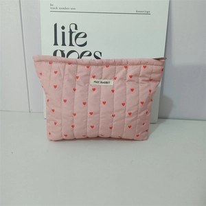 Detail of pink quilted makeup bag featuring red heart patterns and May Rabbit logo