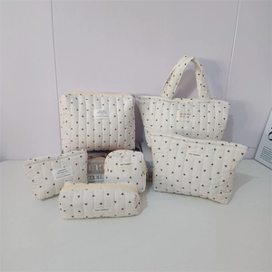Detail of a six-piece cream quilted storage set with heart embroidery and fabric label