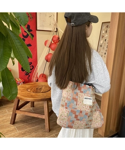 Close-up of ethnic patchwork canvas tote bag with floral patterns and side label