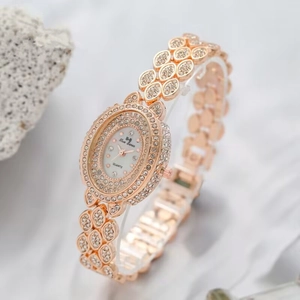 Detail of rose gold oval quartz watch with leaf-shaped rhinestone band and diamond bezel