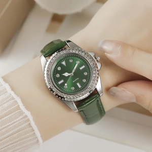 Close-up of green leather watch with rhinestone bezel and sunburst dial worn on wrist