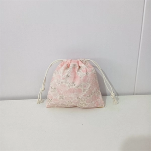 Detail view of pink floral cotton storage pouch with white drawstring closure