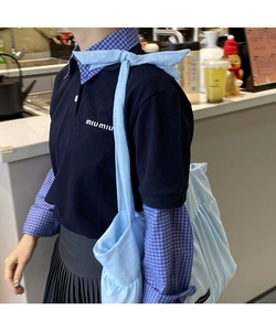 Detail view of a light blue pleated cotton bag paired with a navy layered polo shirt