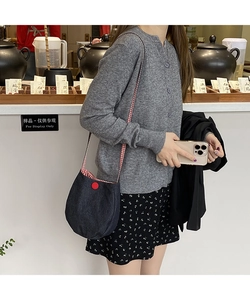 Detail of dark blue denim bag with red button and red-white checkered strap