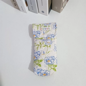 Close-up of quilted floral fabric pouch with button closure and blue flower patterns