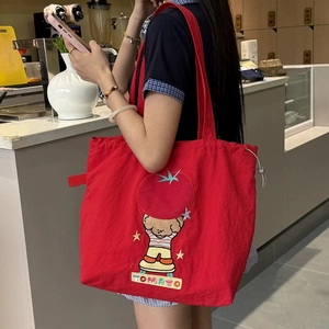 Détail d'un sac cabas rouge en toile avec broderie tomate et cordons de serrage réglables