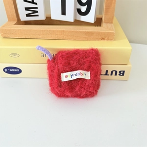 Detail of red plush earphone case with white woven logo label and purple lanyard strap