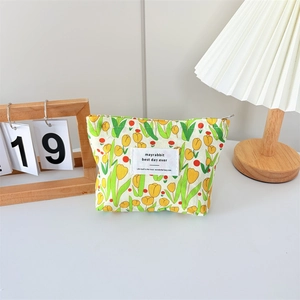 Close-up of canvas makeup bag featuring yellow tulip prints and a woven brand label