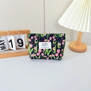 Detailed close-up of blue canvas cosmetic bag with pink tulip print in home setting