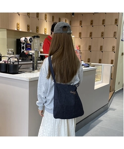 Detail of navy canvas tote bag with gold embroidery shown in a casual lifestyle outfit