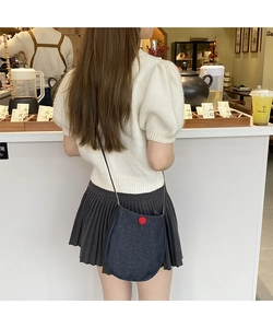 Detailed view of deep blue denim crossbody bag with red button decoration on a model